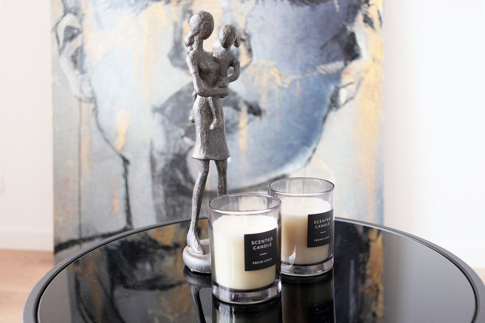 Zwei Kerzen stehen auf einem Tisch vor einem Gemälde.